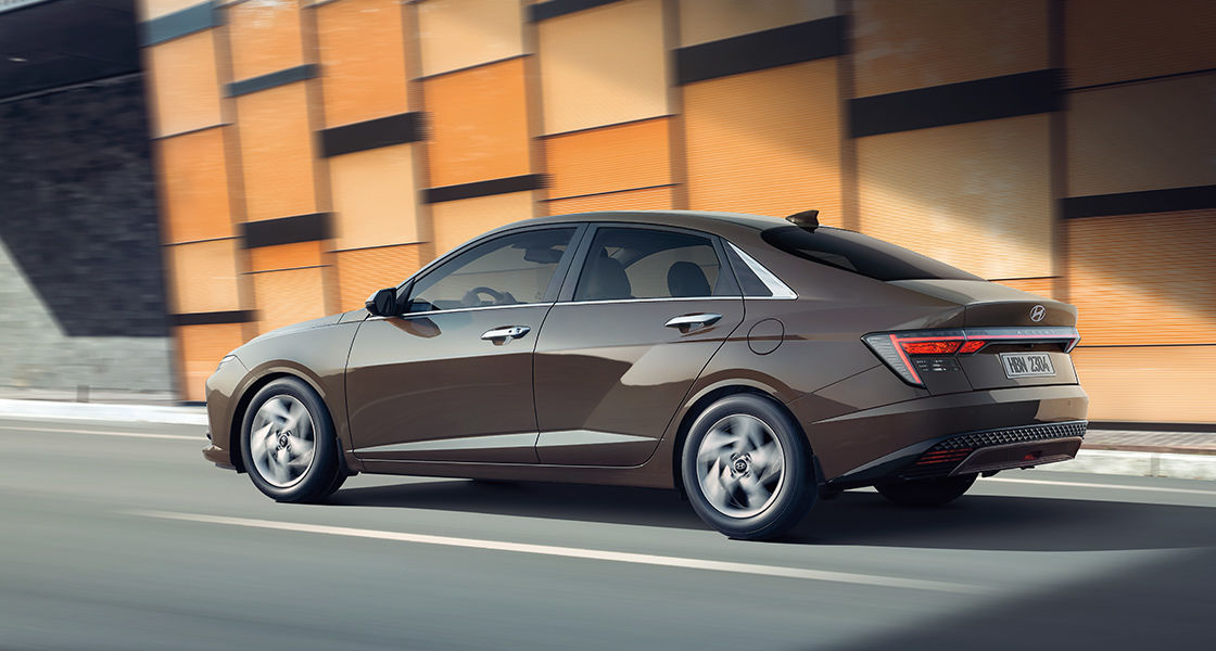 Side-front view of orange Grandi10 with lakeside view at night