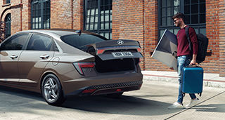 Side-front view of orange Grandi10 with lakeside view at night