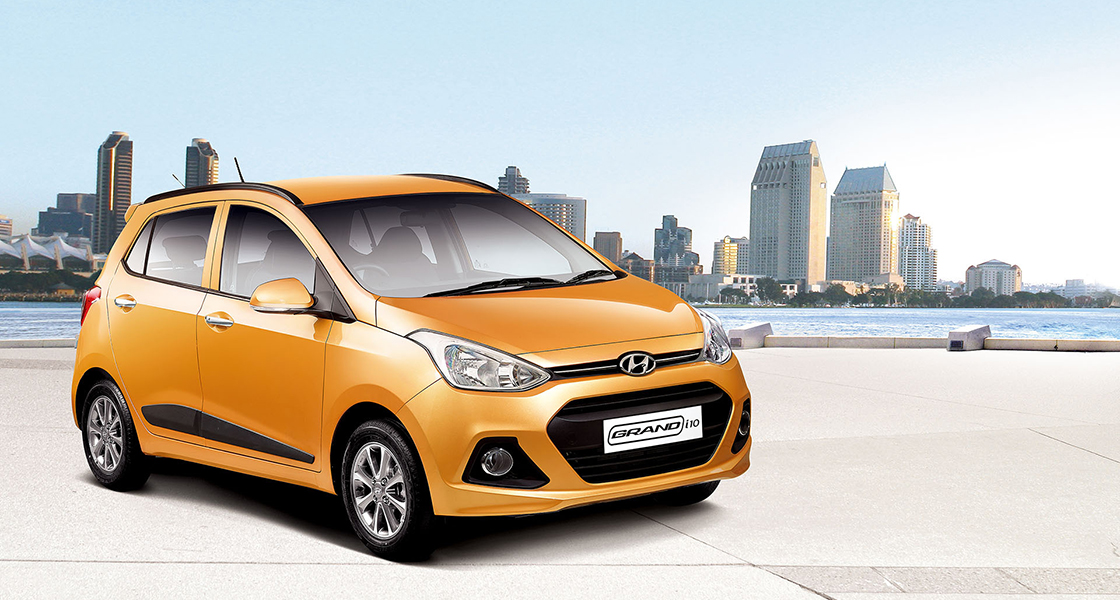 Side-front view of orange Grandi10 with lakeside view at night