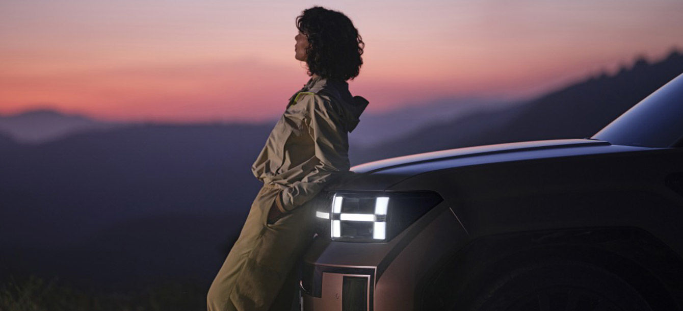 Side-front view of orange Grandi10 with lakeside view at night