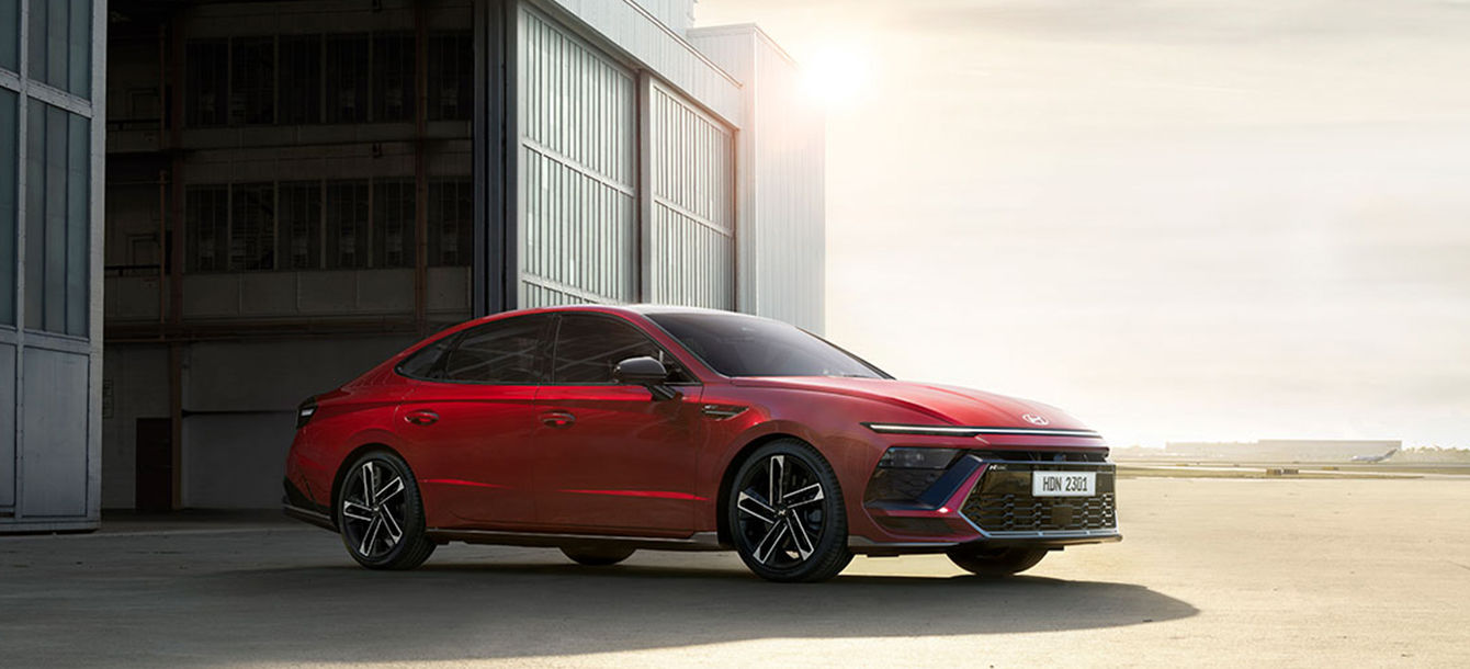 Side-front view of orange Grandi10 with lakeside view at night