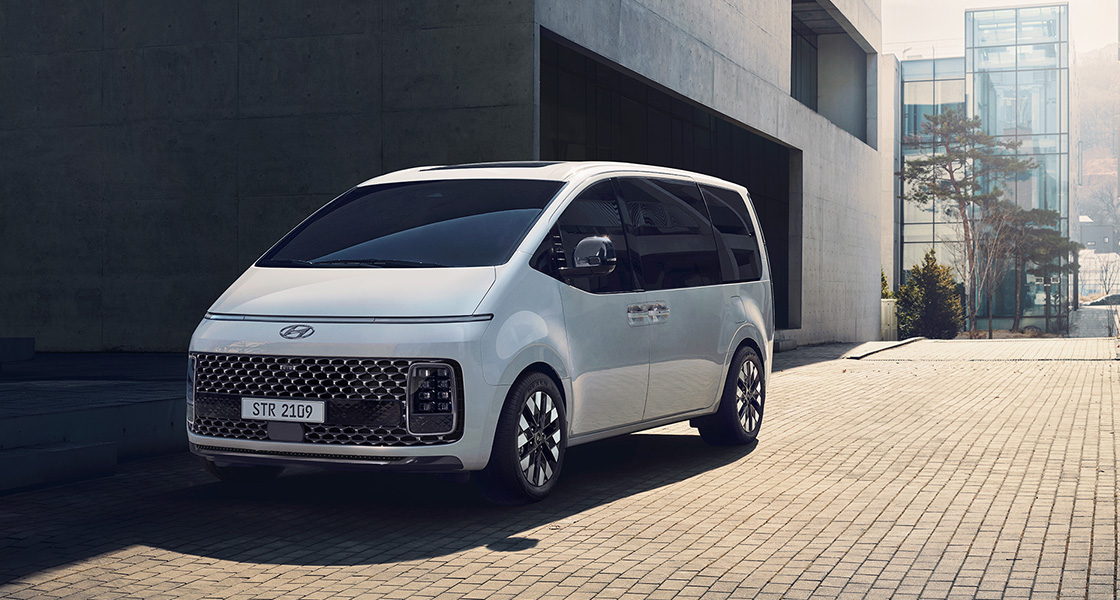 Side-front view of orange Grandi10 with lakeside view at night