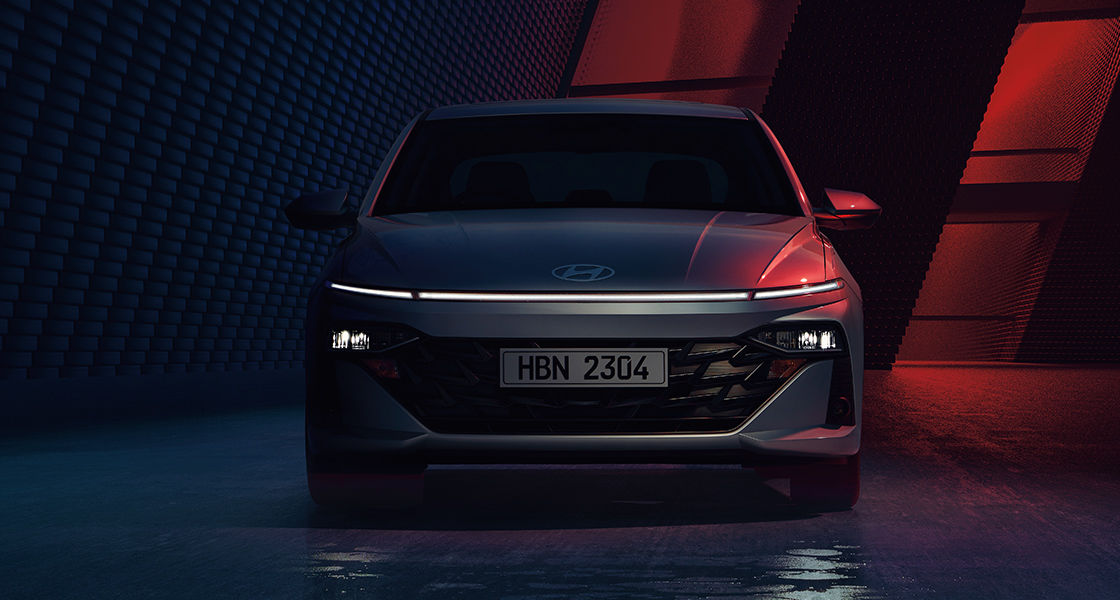 Side-front view of orange Grandi10 with lakeside view at night