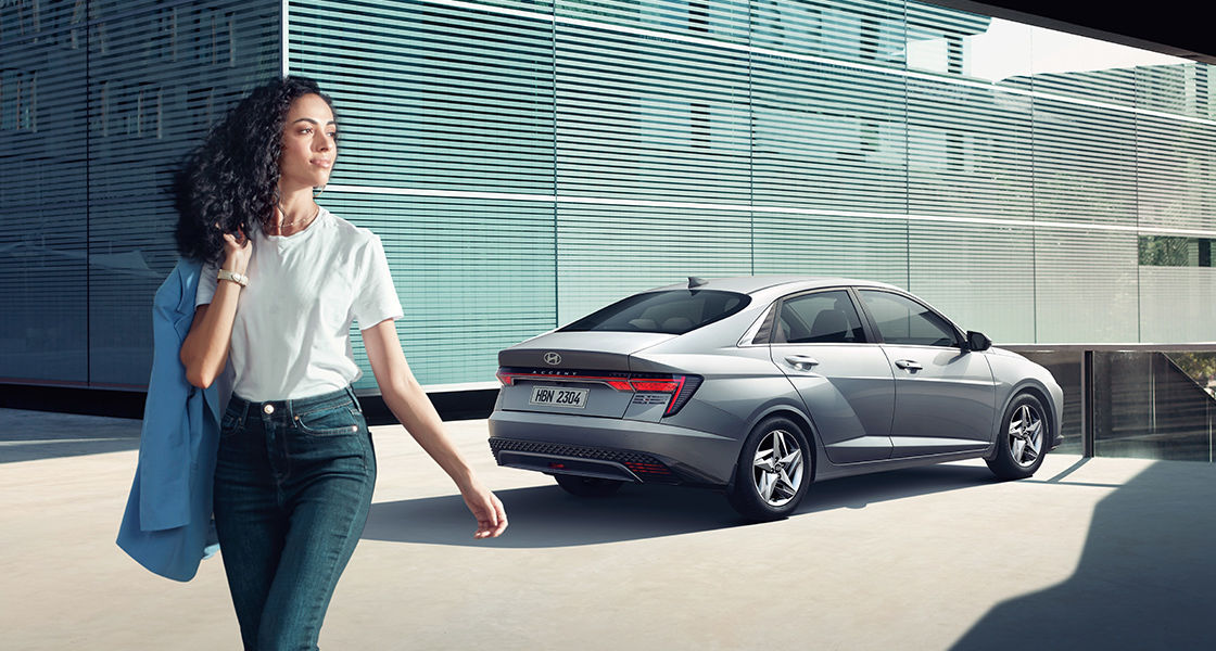 Side-front view of orange Grandi10 with lakeside view at night