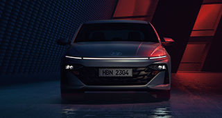 Side-front view of orange Grandi10 with lakeside view at night