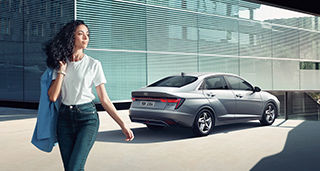 Side-front view of orange Grandi10 with lakeside view at night