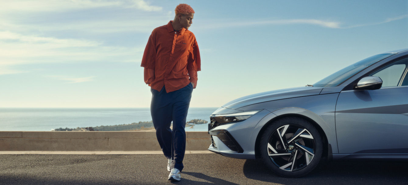 Side-front view of orange Grandi10 with lakeside view at night