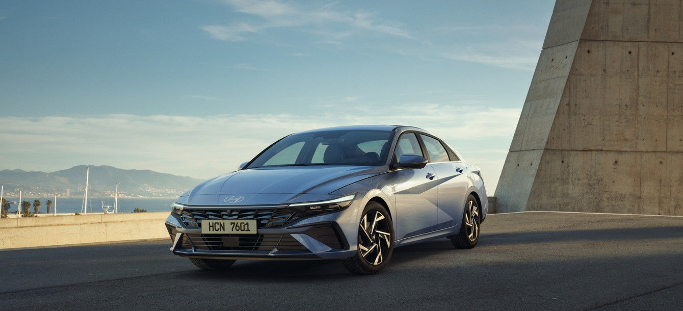 Side-front view of orange Grandi10 with lakeside view at night