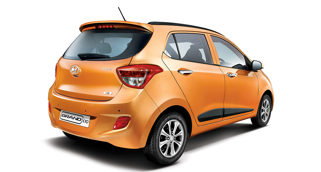Side-front view of orange Grandi10 with lakeside view at night